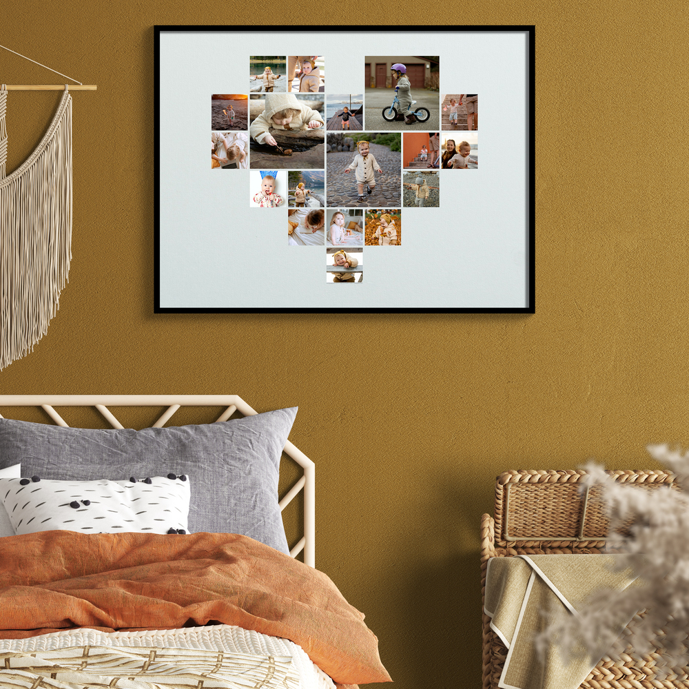 Hartvormige fotocollage met kinderfoto’s in een zwarte lijst boven het bed aan een okergele muur