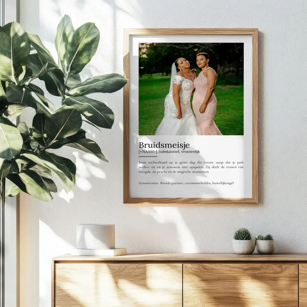 Definitieposter voor een bruidsmeisje met trouwfoto, in een houten lijst aan de muur boven een dressoir