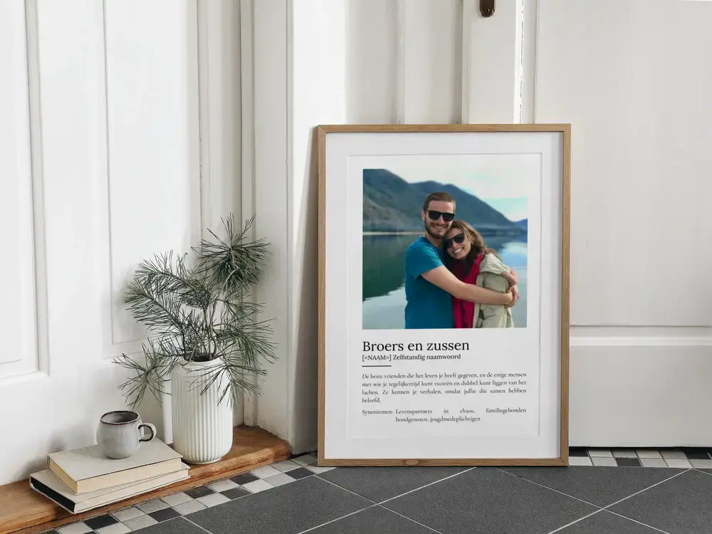 Persoonlijk cadeau voor broer of zus: definitieposter met foto in houten lijst, op de vloer naast een plant