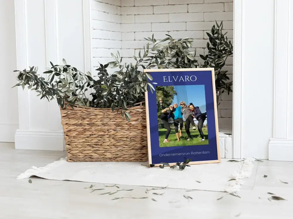 Ingelijste bedrijvenloopposter met teamfoto op blauw, op de vloer naast een plantenmand, als bedankje voor het team
