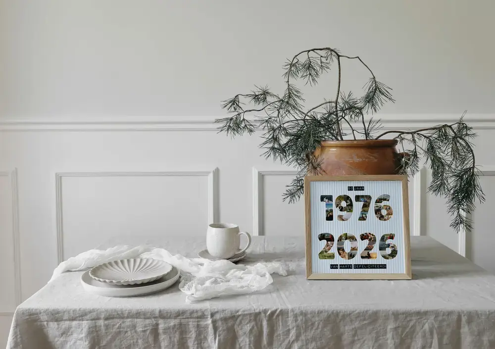 Fotocollage met jaartallen van kleine foto's in een lichte houten lijst op een gedekte tafel naast een plant