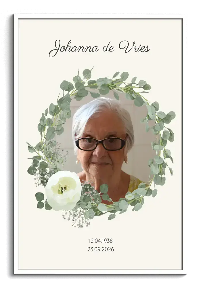 Persoonlijk gedenkportret met naam, eucalyptuskrans en witte bloemen in een witte lijst