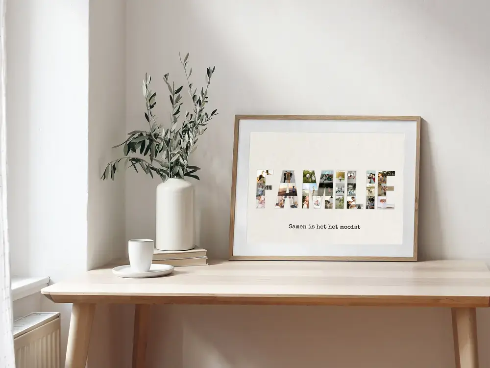 Fotocollage van familiefoto’s in lettervorm met spreuk, in een houten lijst op een bureau naast een vaas en kopje