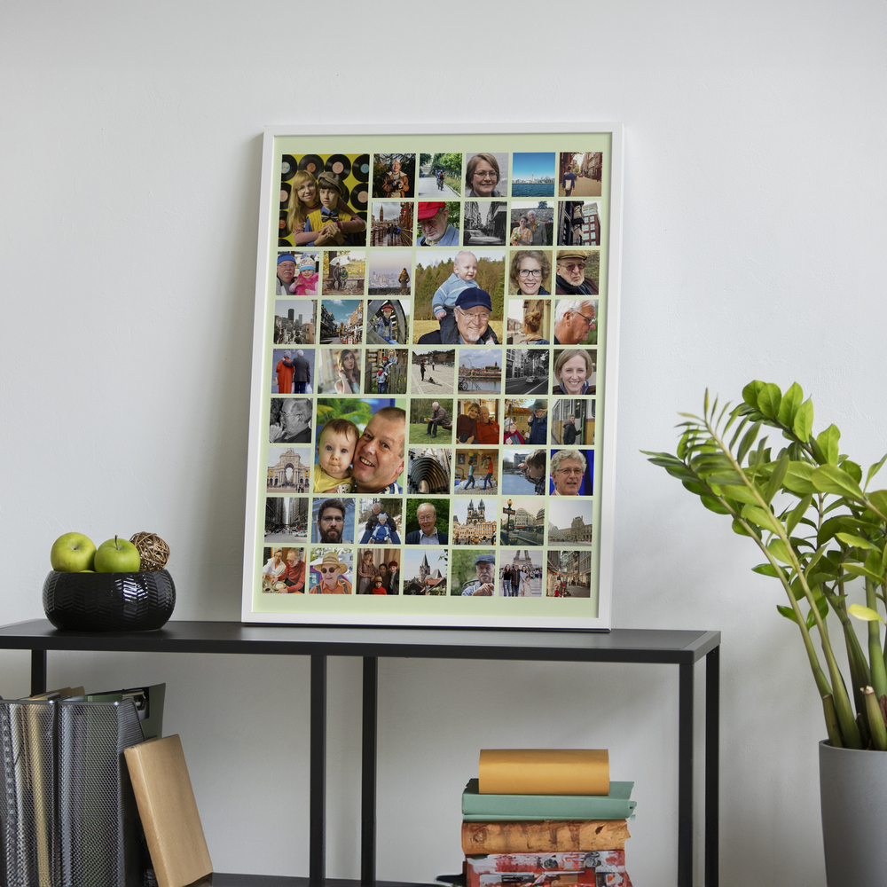 Familieposter in een witte lijst op een zwarte kast, met grote en kleine foto's op een lichtgroene achtergrond