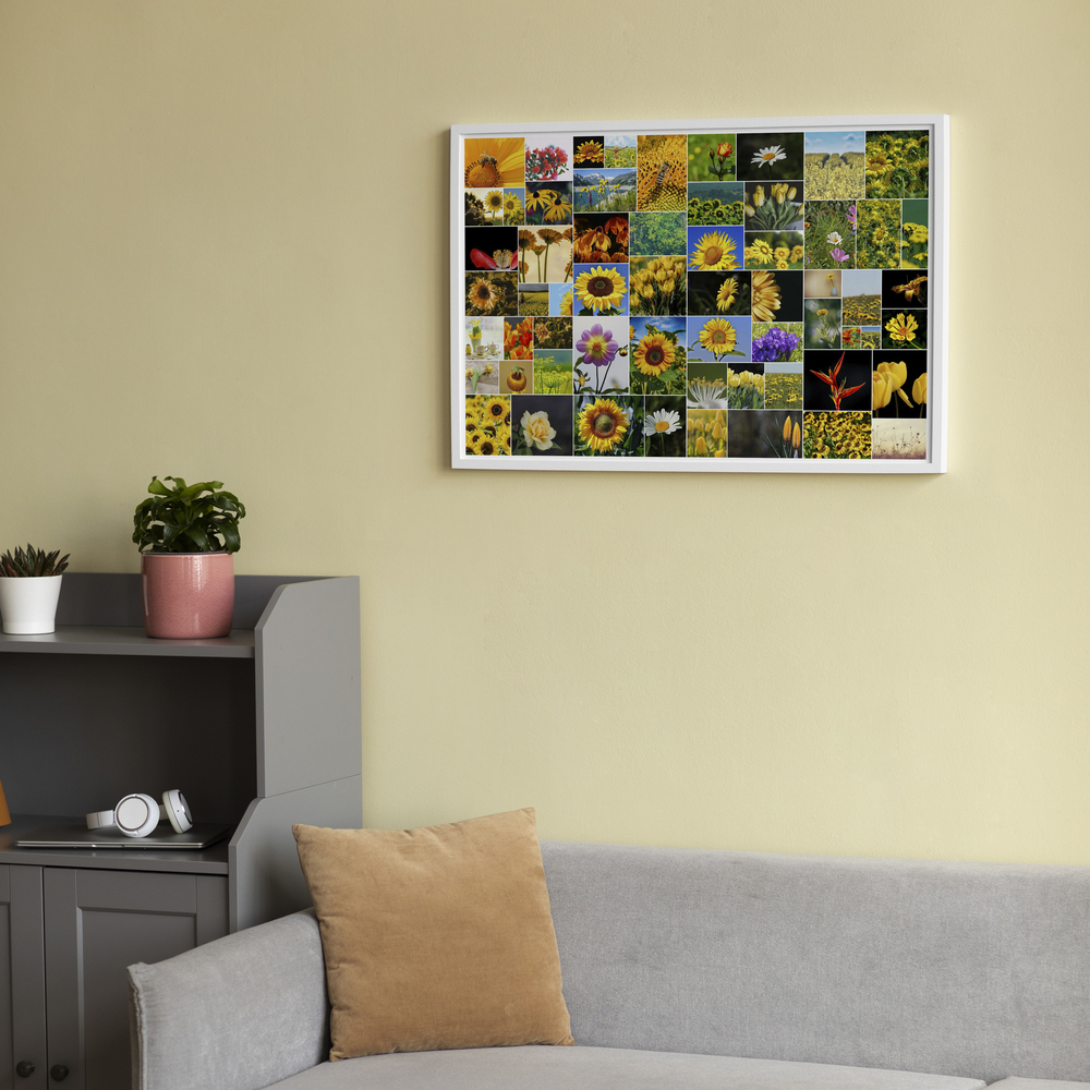 Fotocollage met bloemenfoto’s van verschillende formaten in een witte lijst, boven een grijze bank aan een lichtgele muur